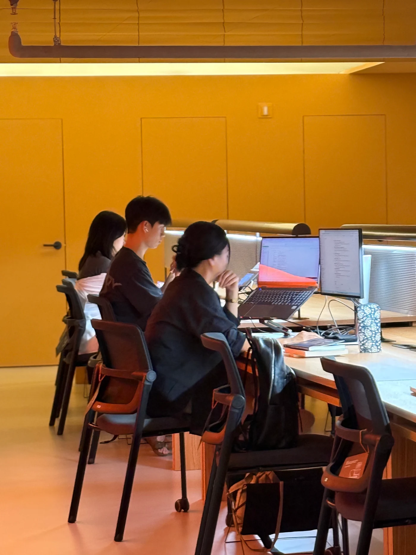 따뜻한 조명 아래 각자의 노트북 작업에 집중하는 지하 라운지 이용객